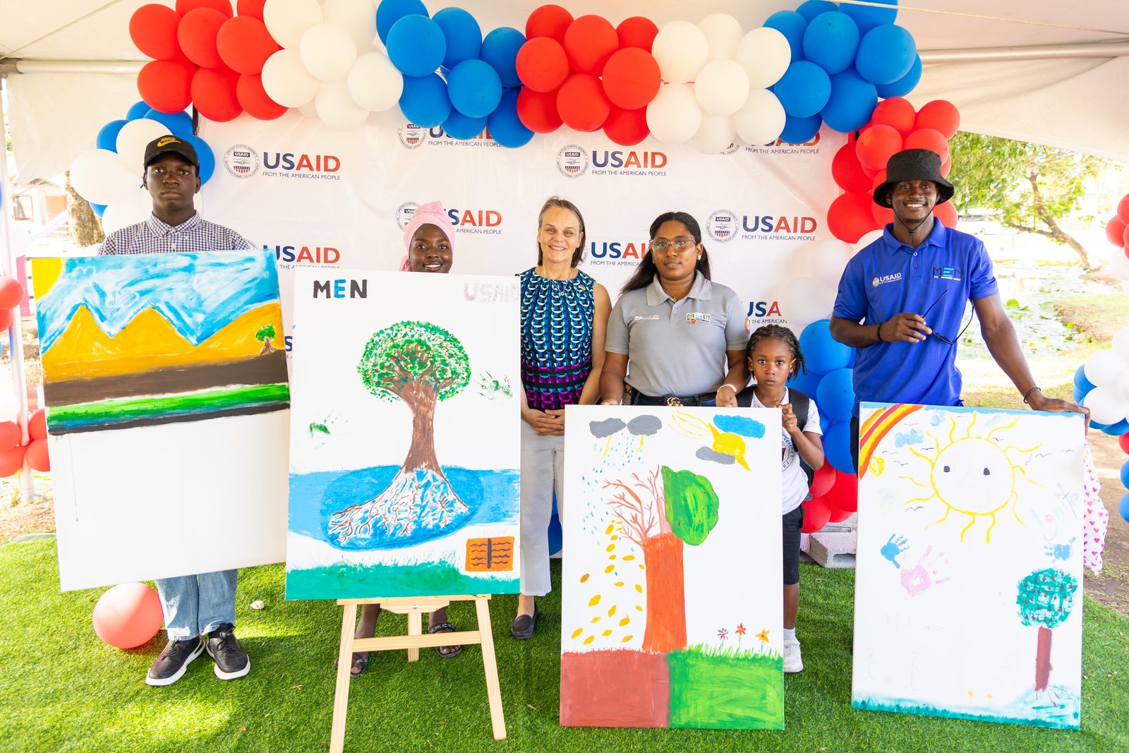 Youth Diversion Programme participants present their artwork alongside the US Chargée d'Affaires and partners